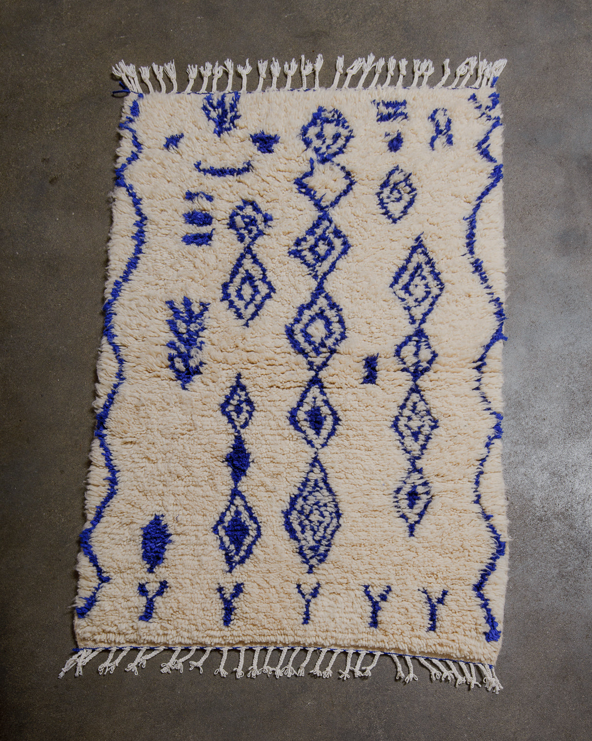 Cream and blue patterned rug on a gray floor